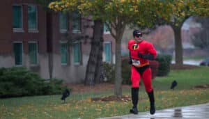 A person dressed as Mr. Incredible from the Pixar movie 'The Incredibles' runs at the Halloween 5k held at Moraine Valley Community College.|A group gathers for a photo during the Halloween 5K at Moraine Valley Community College.