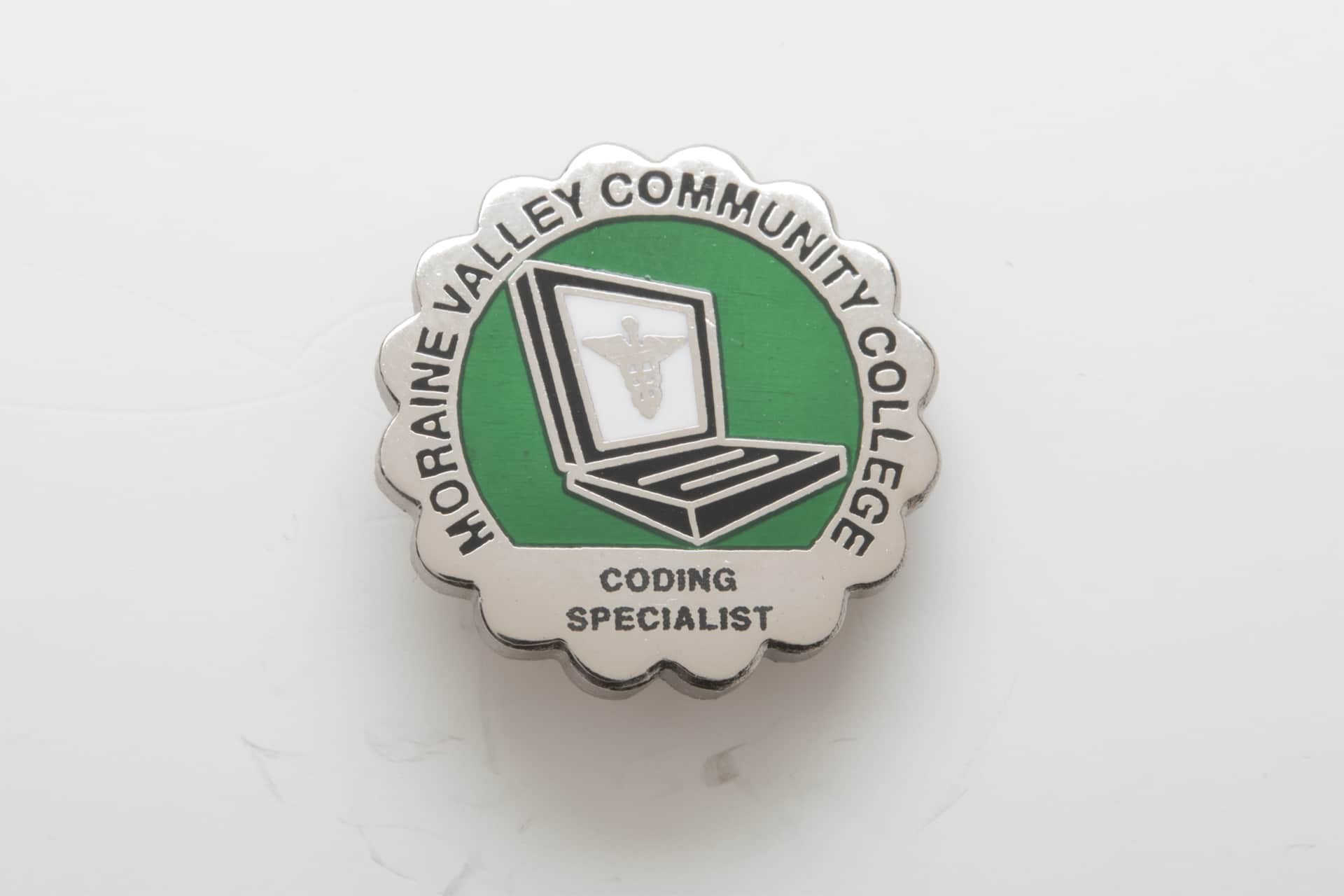 Medical Coding Enamel Pin. A silver circle with a laptop and medical symbol. 