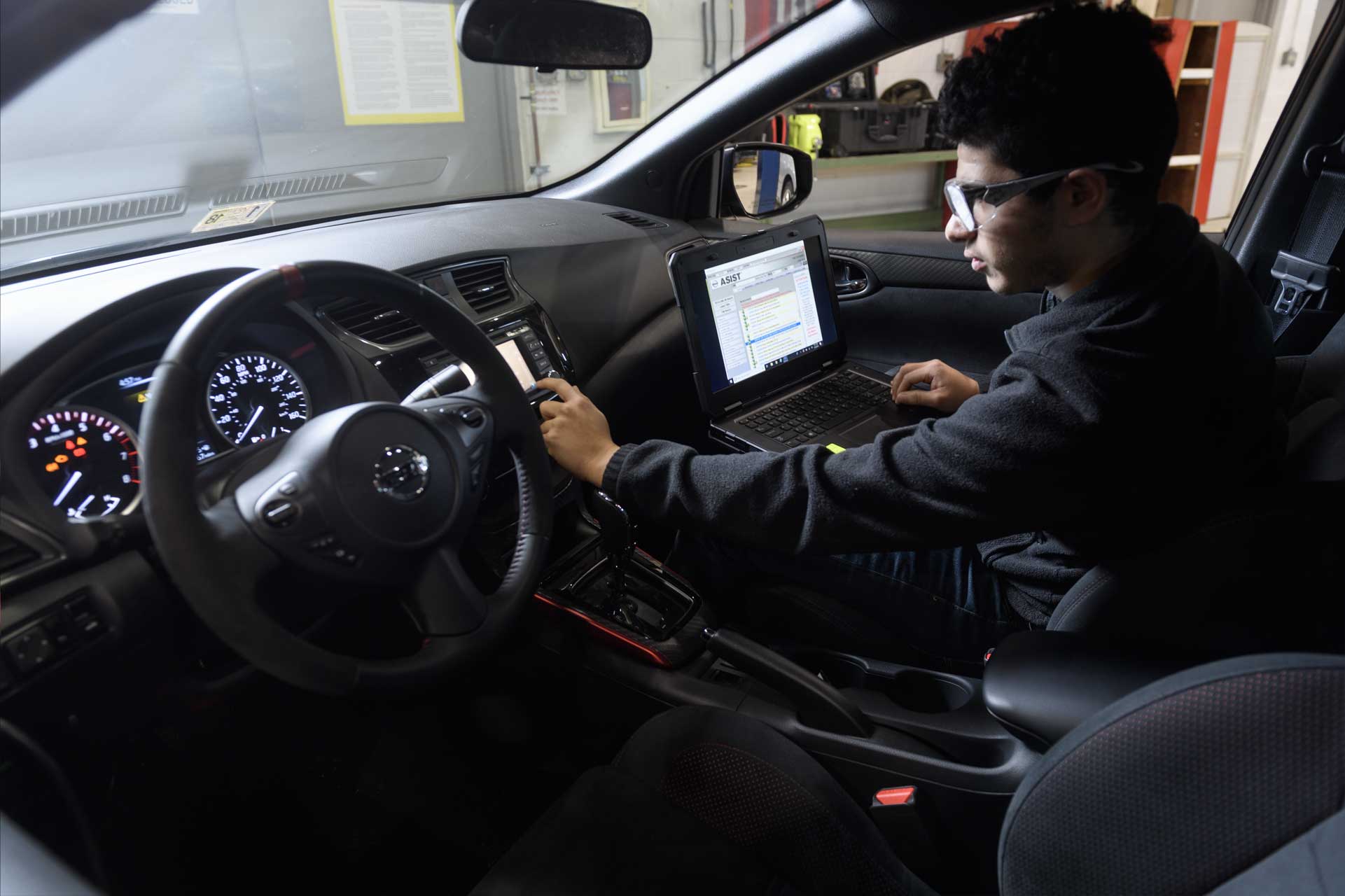 man sitting in car with laptop working on interface