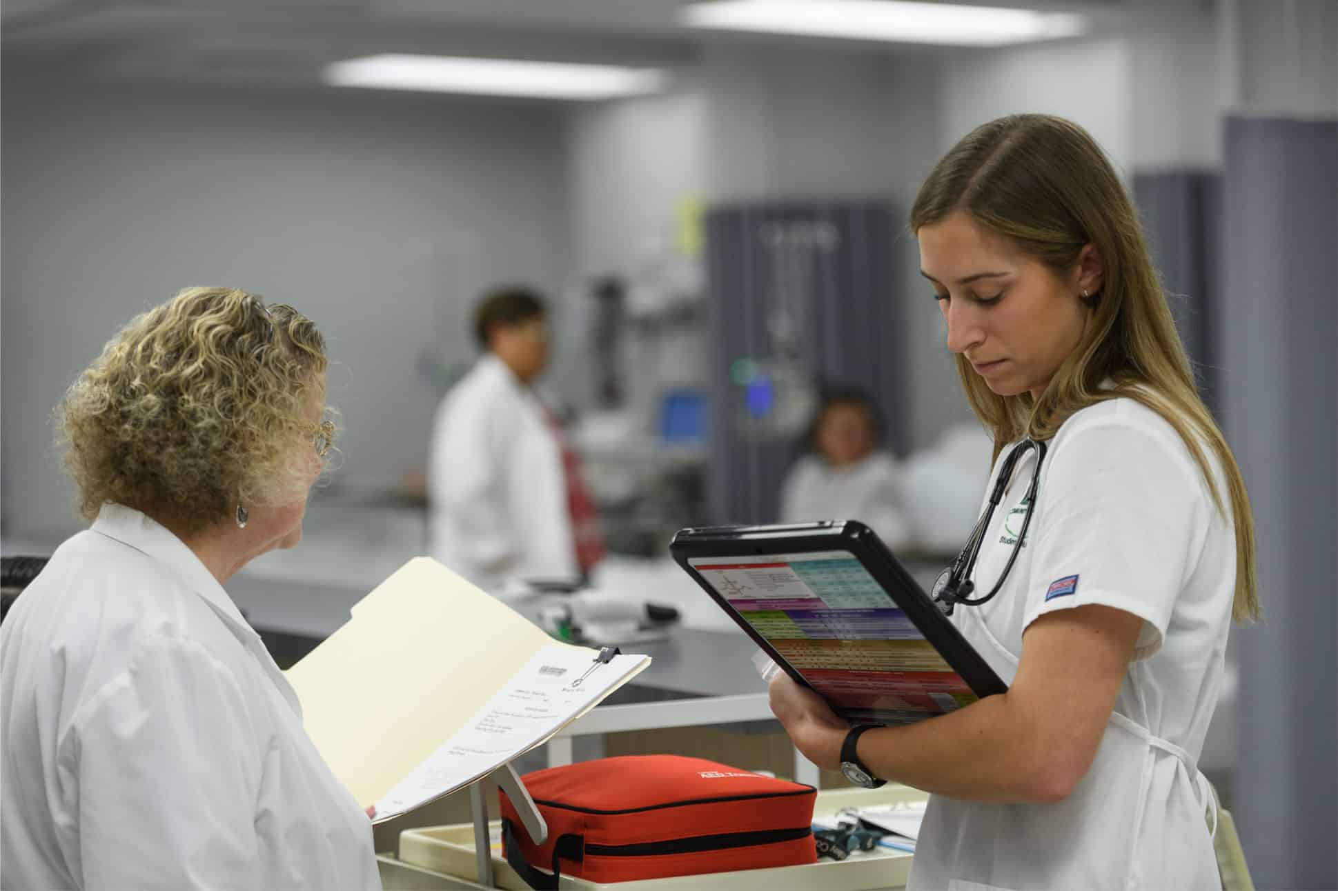 Nursing student standing at desk with clipboard