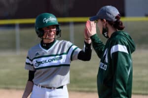 A Moraine Valley softball player high-fives her coach out on the field during a game.