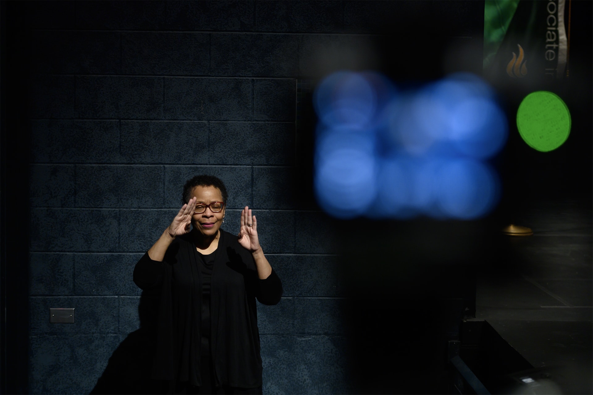 Woman using ASL in theater to interpret a show.