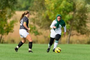 Two soccer players chase after the ball during a game