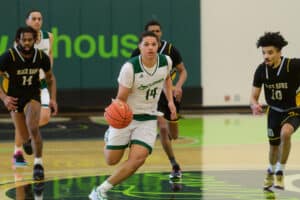 A men's basketball player dribbles the ball surrounded by other players on the court during a game