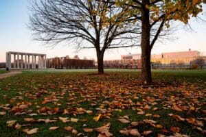 A view of campus and the Gateway in the fall at dusk with leaves on the ground
