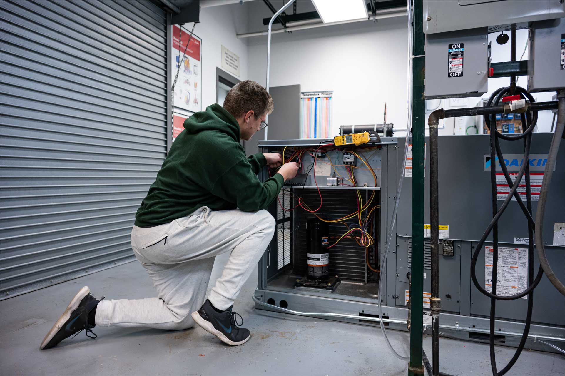 man standing at air conditioning unit with door panel open