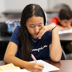 teen writing on a piece of paper in class