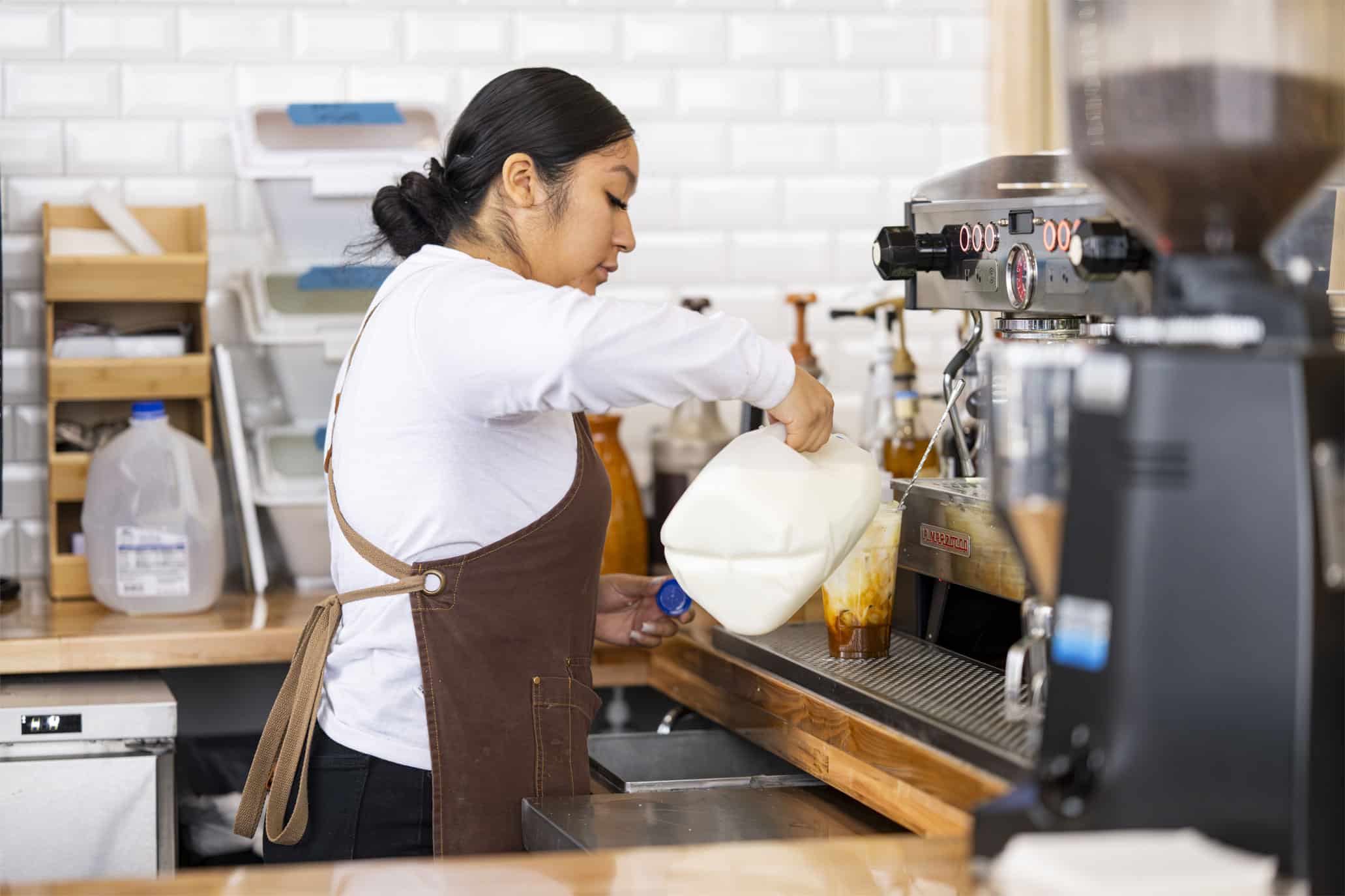 Barista pouring milk into a latte