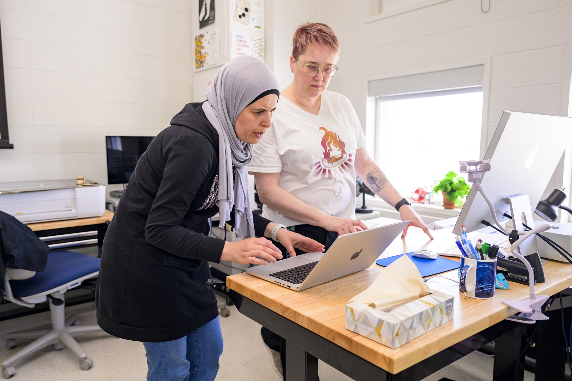 Student looking at computer with faculty member in digital design studio