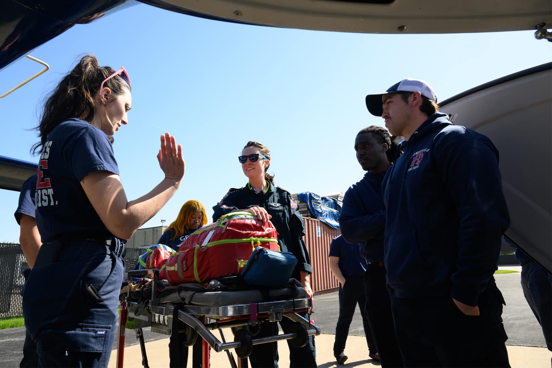 Group of paramedic students standing outside of the ambulance next to a stretcher