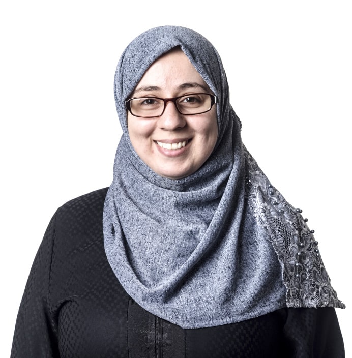 Person wearing glasses and a gray headscarf posed against a white background
