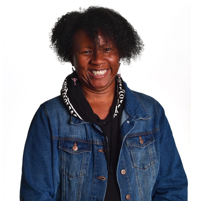 Person wearing a denim jacket and dark top, posed against a white background