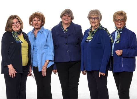Five people standing together in coordinated blue outfits against a white background