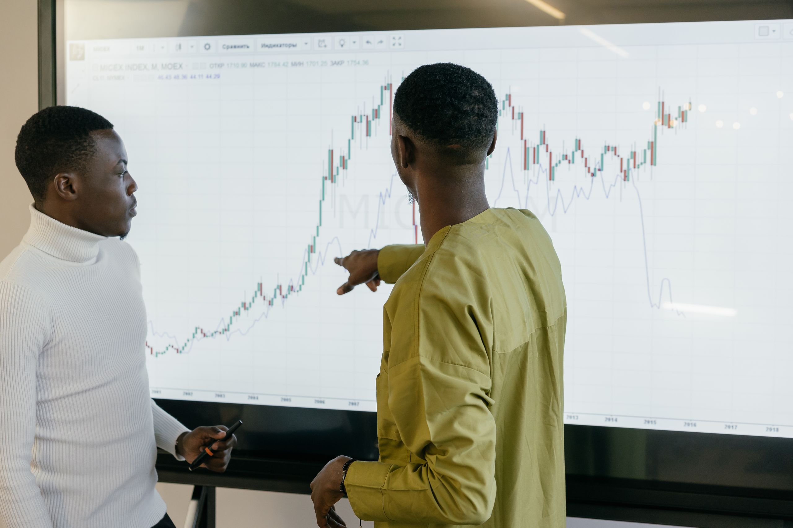 Two professionals discussing financial trends on a graph at the office.